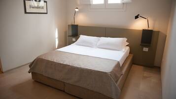 A neatly made bed with a beige bedspread, two bedside lamps, and a framed picture on the wall.