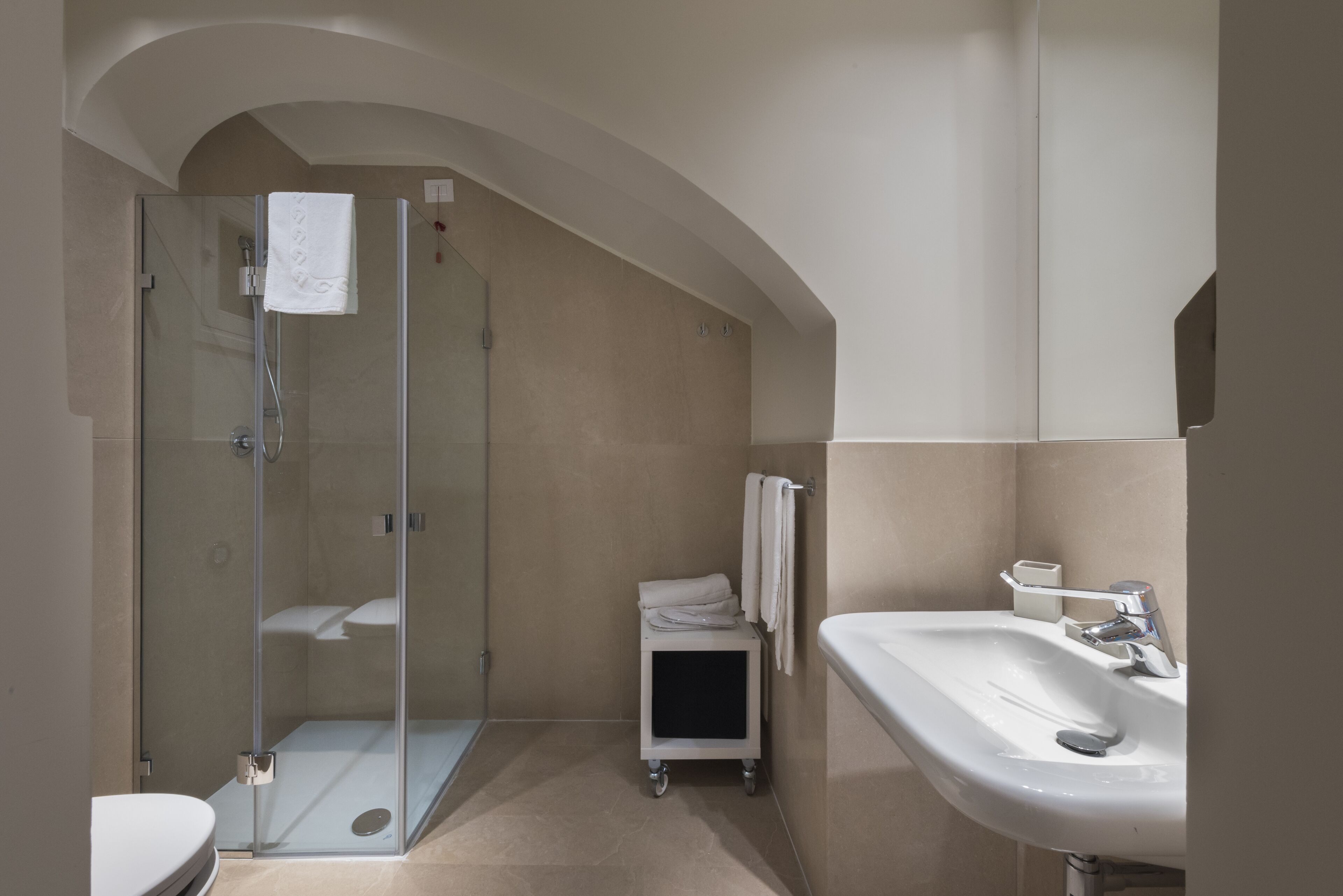 Un baño moderno con ducha de vidrio, lavamanos blanco y retrete.
