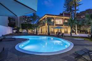 Una piscina al aire libre, sombrillas, tumbonas