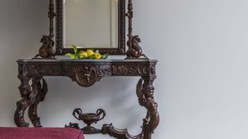 Una habitación con una consola de madera oscura, un espejo y un banco tapizado en rojo.