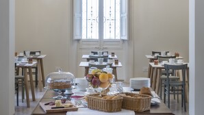 A dining area with a chandelier, tables, chairs, and a window with a view. - Giardini Mon Plaisir (Trapani)