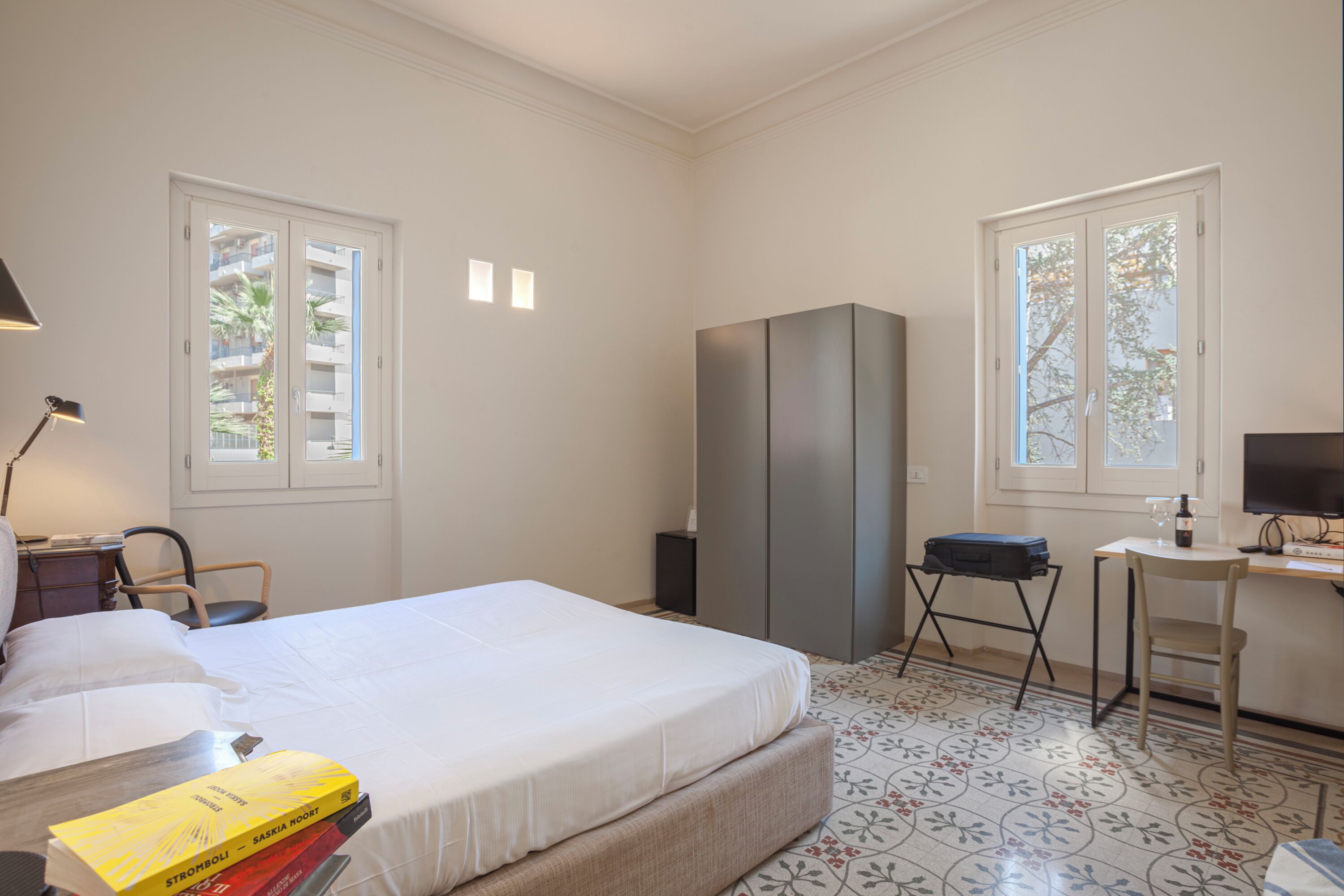 A bedroom with a bed, a desk, a chair, a wardrobe, and a lamp.