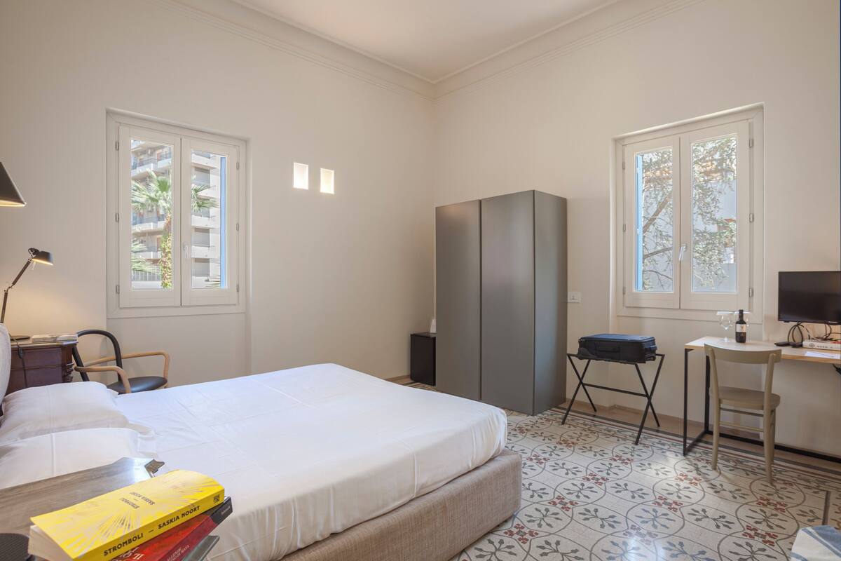 Un dormitorio con cama, escritorio, silla, armario y lámpara.