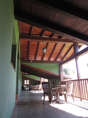An indoor wooden deck with tables and chairs, a hanging lantern, and a view of the outside. - Casa Rural Kerizara (Otxandio)