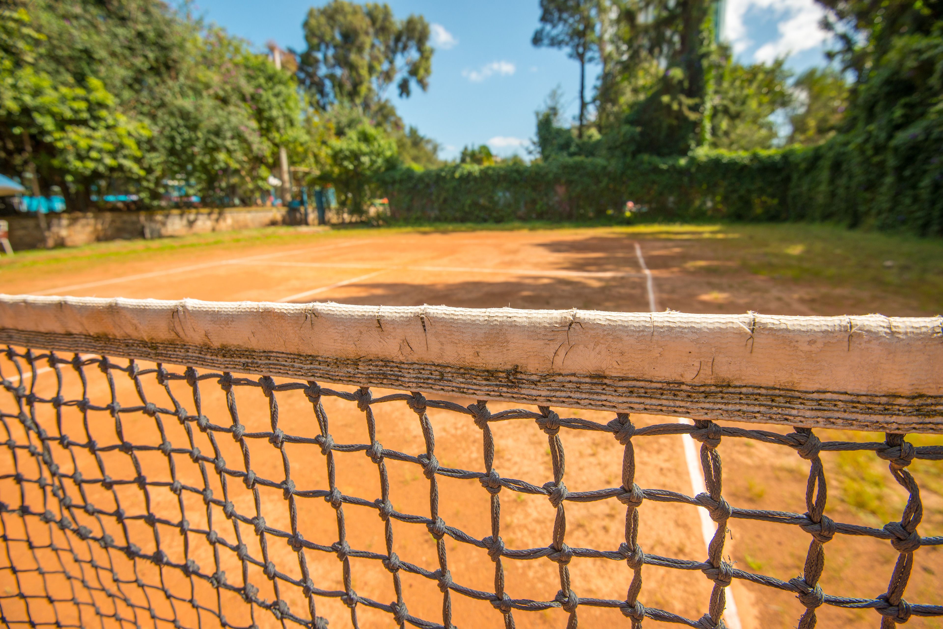 A tennis court with a net in the foreground.