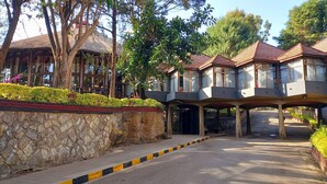 A hotel entrance with a stone wall, a paved pathway, and a covered walkway with glass railings. - Ghion Hotel (Addis Ababa)