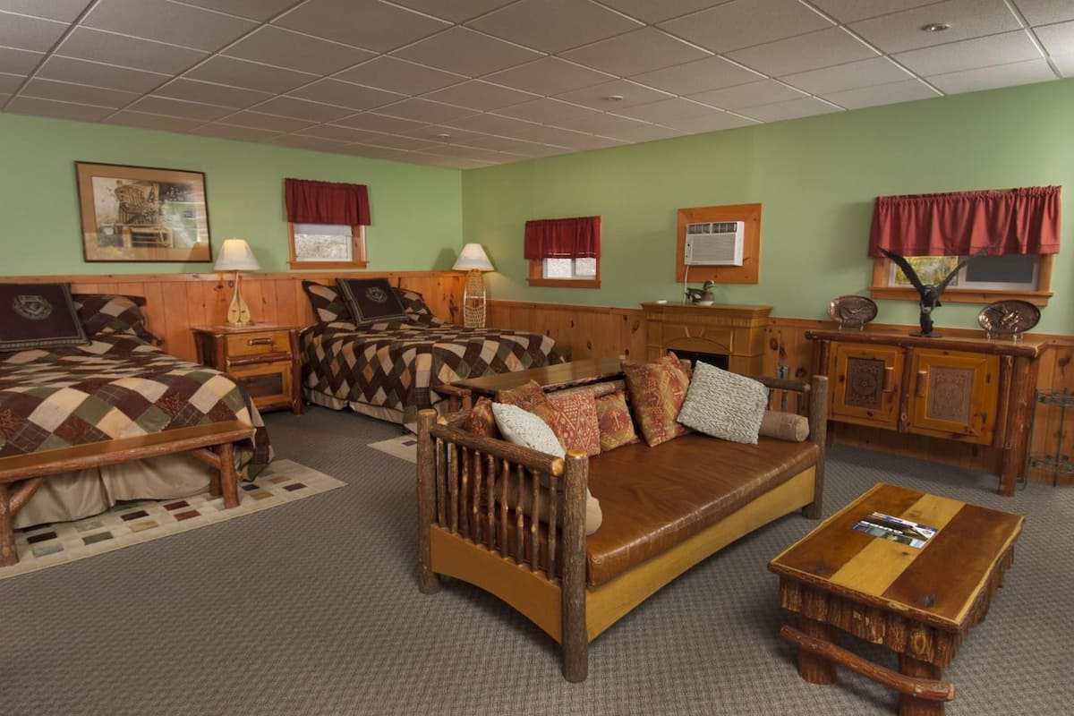 A room with a large bed, a sofa, a wooden coffee table, and a desk with a lamp.
