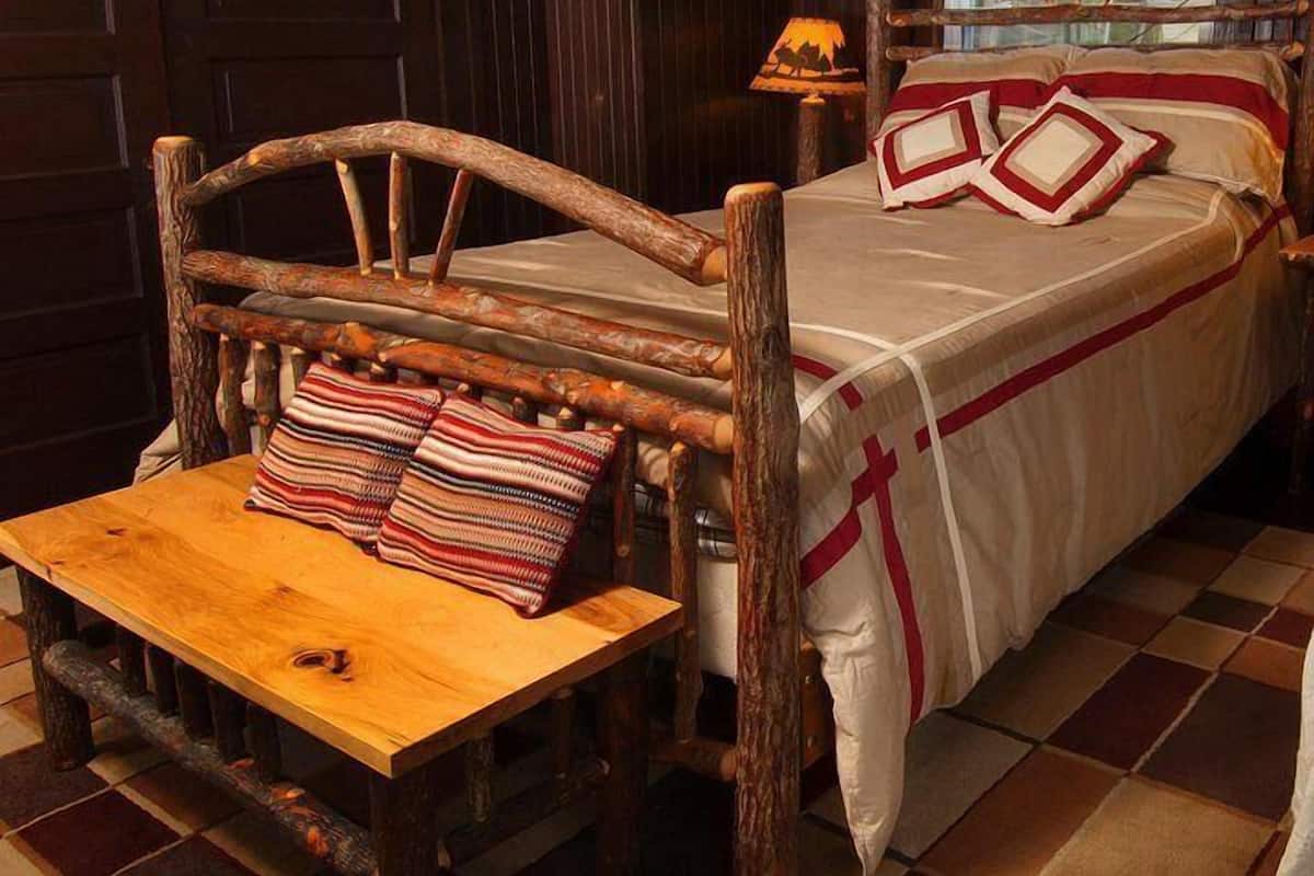 A rustic wooden bed with a headboard, a bedside table, and a lamp.