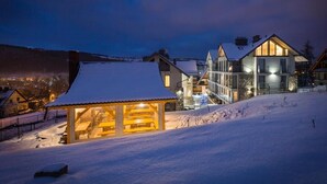 A snow-covered landscape with a lodge featuring a wooden structure and a modern building with large windows. - Smrekowa Polana Resort & Spa (Zakopane)