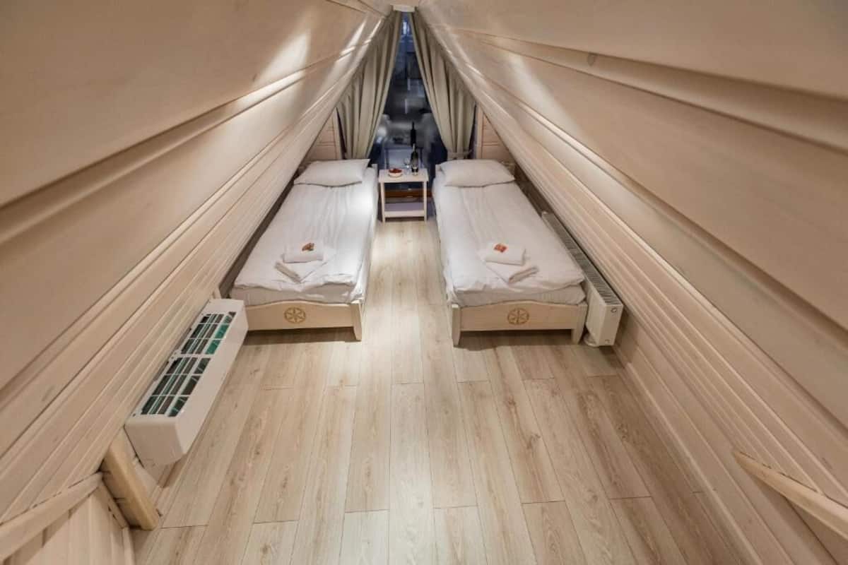Ett litet rum med två sängar, ett litet bord och en luftkonditioneringsanläggning.