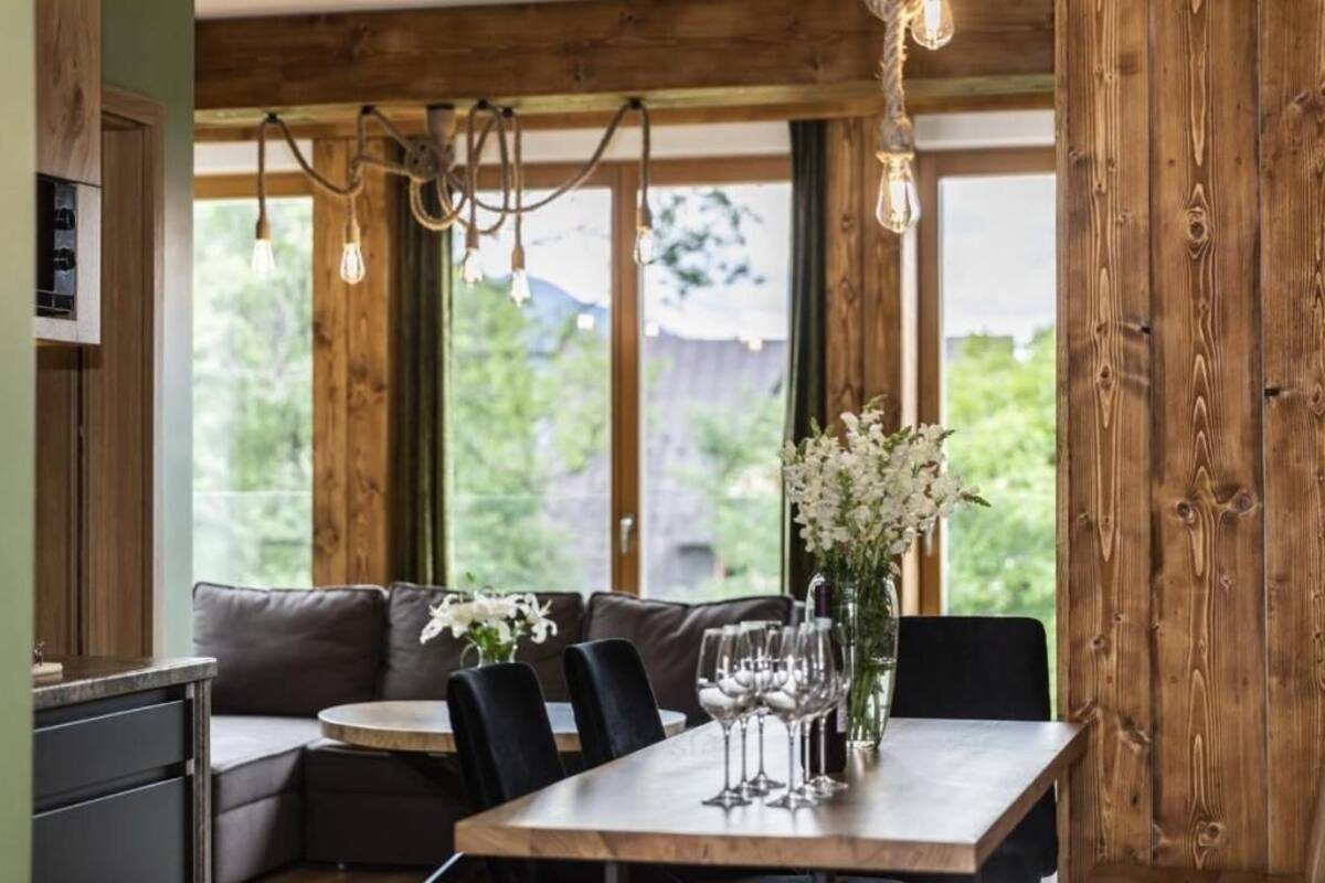 En matplats med ett träbord, stolar, en soffa och en vas med blommor.