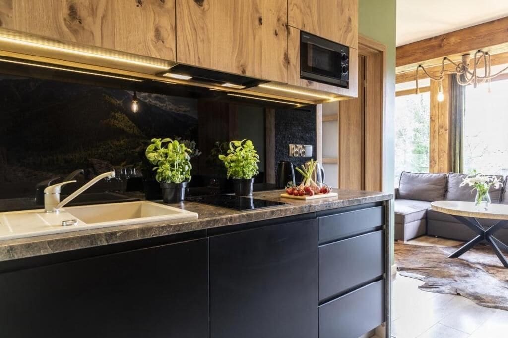 Una cocina moderna con cubierta negra, armarios de madera y microondas integrado.