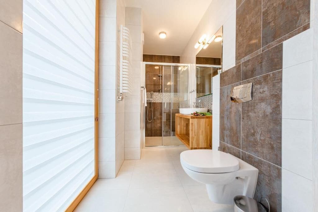 A modern bathroom with a toilet, shower, and glass-enclosed shower area.