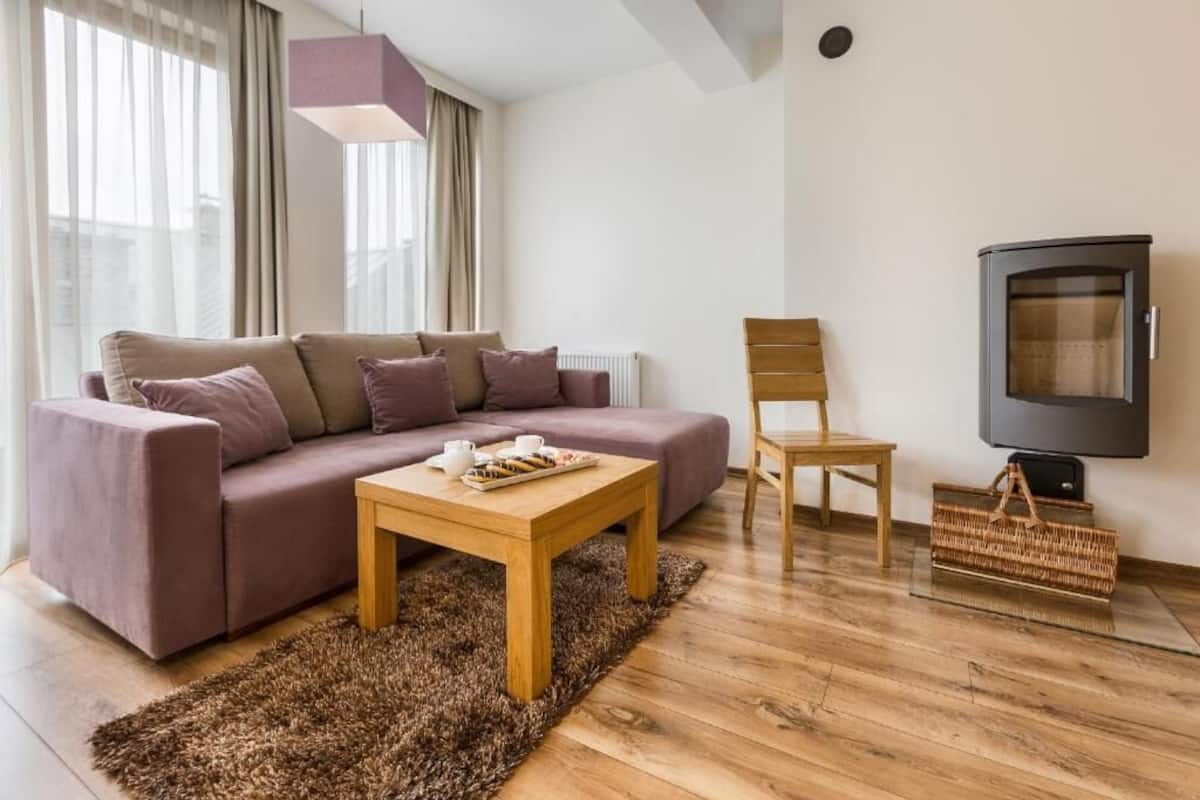 Ett modernt vardagsrum med en soffa, ett soffbord i trä, en korg av rotting, en stol i trä och en tv.