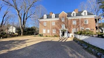 A large brick building with a symmetrical facade, multiple windows, and a central entrance with a porch.