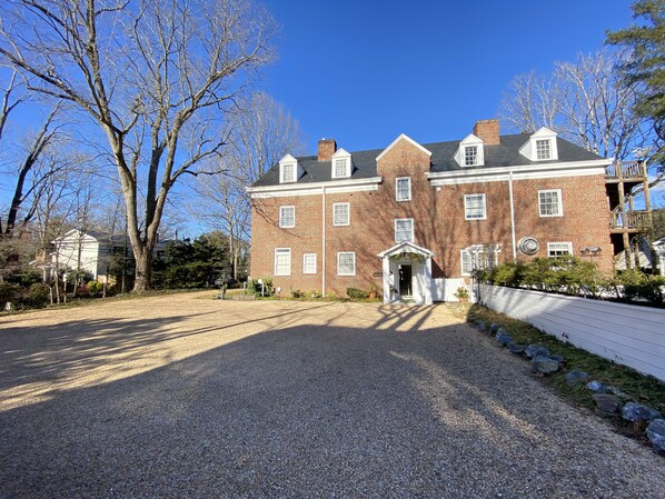 A large brick building with a symmetrical facade, multiple windows, and a central entrance with a porch.