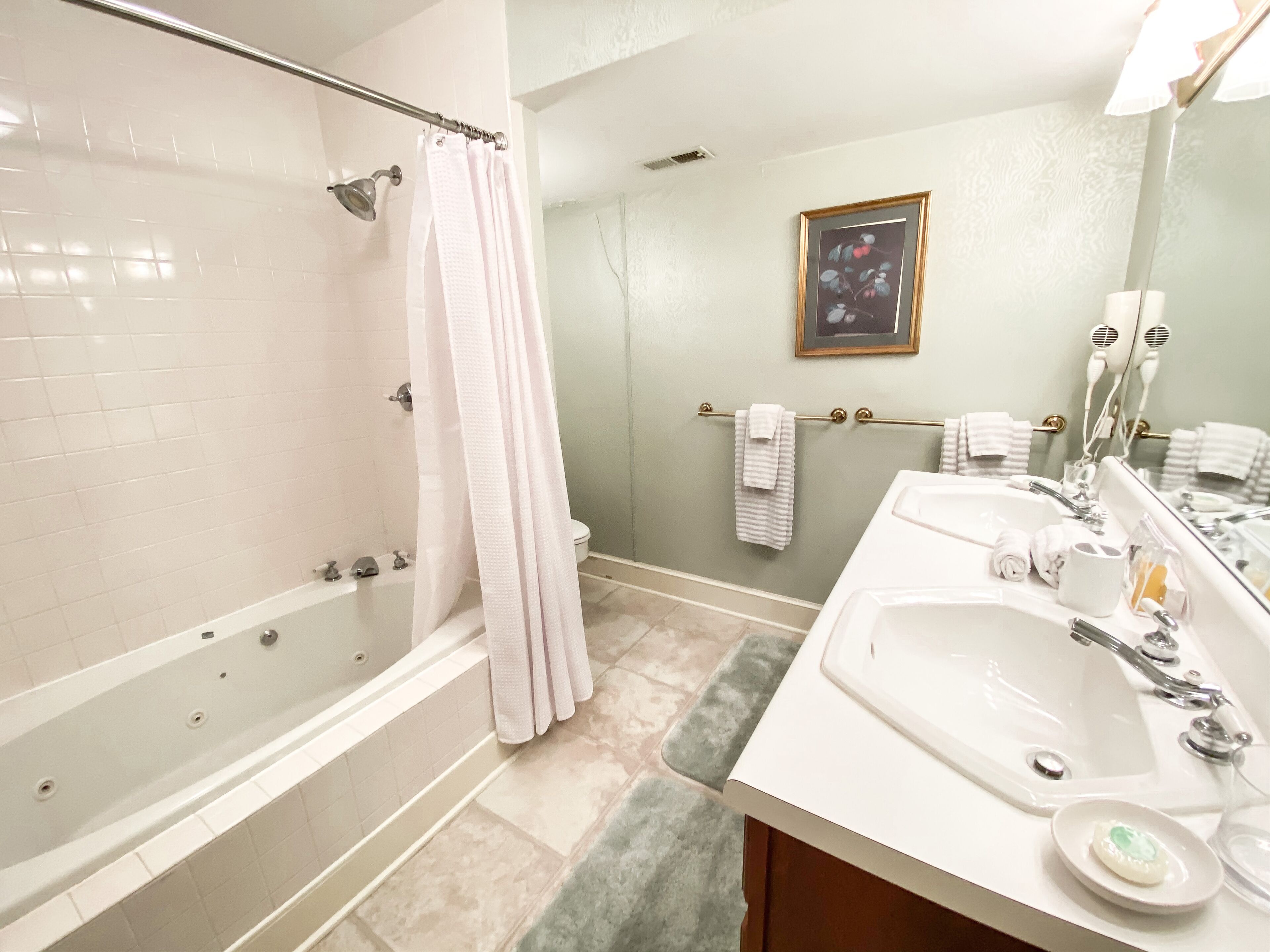 A bathroom with a bathtub, a shower, a sink, and a mirror.