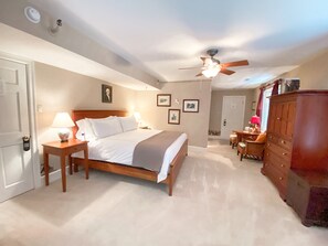 A bedroom with a bed, bedside tables, a dresser, and a ceiling fan.