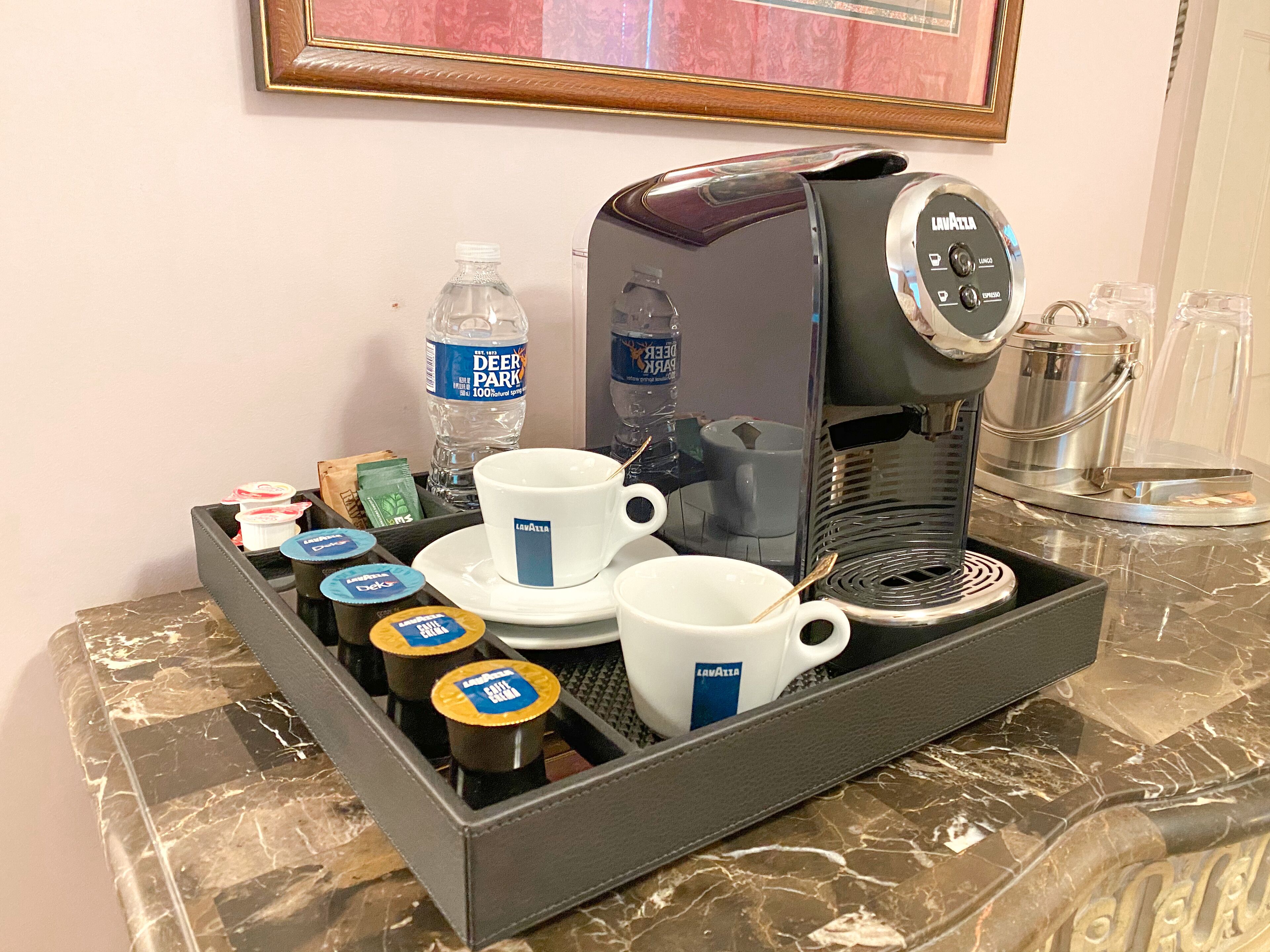 Una estación de café con cafetera, tazas y cápsulas de café.