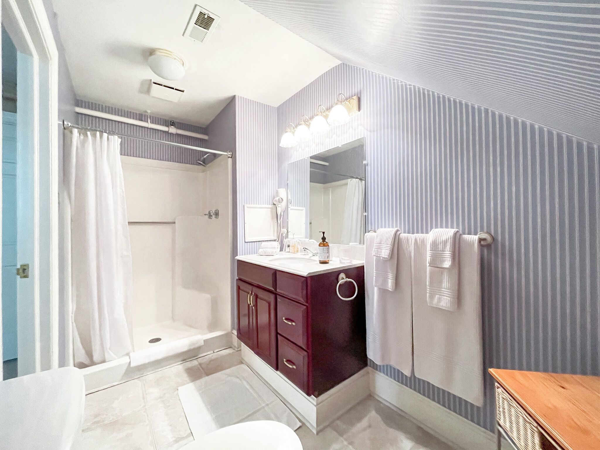 A bathroom with a shower, vanity, and a mirror.