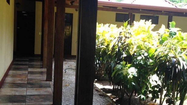 A corridor with tiled flooring leading to a covered outdoor area with a garden. - Hotel Flor de Itabo (Sardinal)