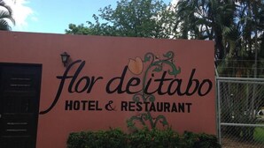 A sign for Flor delitabo Hotel & Restaurant with a decorative floral design. - Hotel Flor de Itabo (Sardinal)