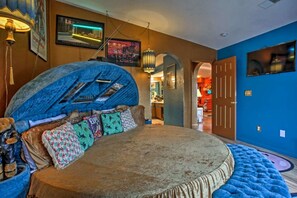 Un dormitorio con una cama grande, una pared azul y una puerta que da a otra habitación.
