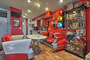 Una habitación con temática retro, con muebles rojos y blancos, una vitrina de cristal con recuerdos y un cartel de Coca-Cola en la pared.