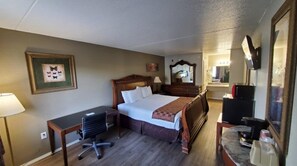A hotel room with a bed, desk, chair, and a mirror.