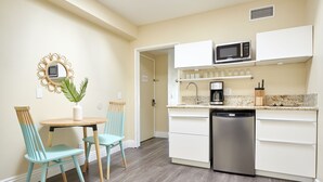 A compact kitchen with a microwave, coffee maker, and dishwasher. There is a small dining table with chairs and a potted plant. - Kasa Gaslamp Quarter San Diego (San Diego)