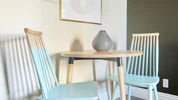 A room with two light blue chairs, a round wooden table, and a framed abstract artwork on the wall.