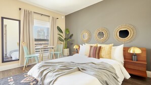 A modern hotel room with a large bed, a view of a cityscape, a balcony, and decorative wall mirrors. - Kasa Gaslamp Quarter San Diego (San Diego)