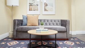 A living room with a grey sofa, a round coffee table, and two framed pictures on the wall. - Kasa Gaslamp Quarter San Diego (San Diego)
