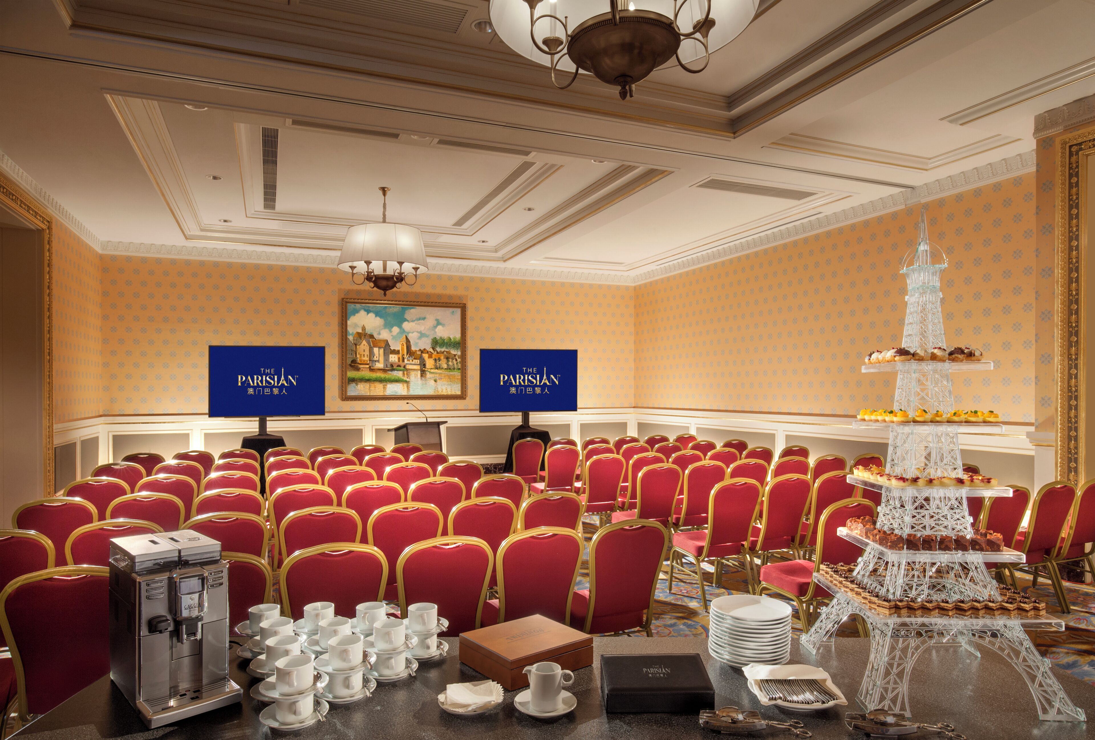 Ein Konferenzraum mit roten Stühlen, einer Kaffeemaschine und einer gestuften Dessertauslage.