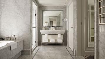 A modern bathroom with a marble sink, a large mirror, and a vanity with three towel racks.