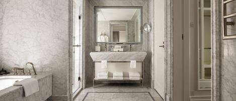 A modern bathroom with a marble sink, a large mirror, and a vanity with three towel racks.