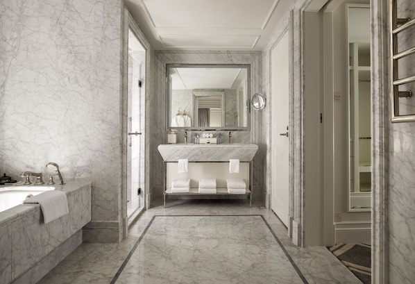 Un baño moderno con lavamanos de mármol, un espejo grande y un mueble de tocador con tres toquilleros.