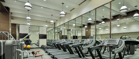 A gym with treadmills, weight machines, and exercise balls.