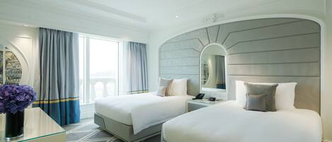 Habitación de hotel con dos camas, un espejo grande y vistas a la ciudad.
