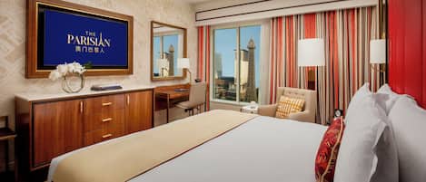 A hotel room with a large bed, a desk, a chair, a TV, and a view of the Eiffel Tower.