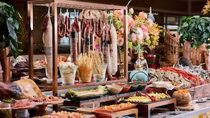 Un bufé con diversas opciones de comida, incluyendo carnes, quesos y verduras.