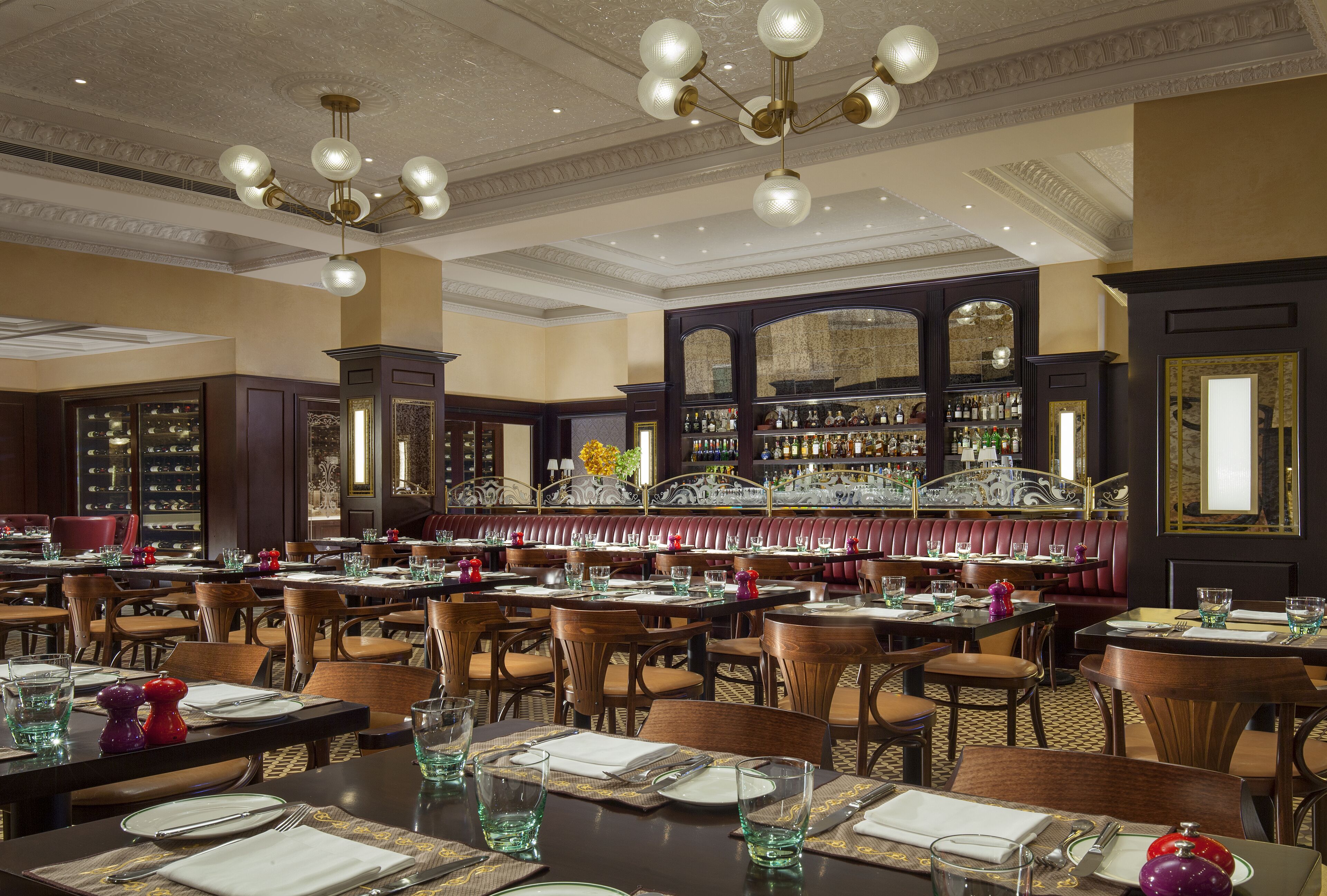 A restaurant with multiple tables, chairs, and a bar area with shelves of bottles.