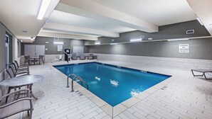 Une piscine avec une terrasse carrelée, des chaises longues et un poste de surveillance pour le sauveteur.
