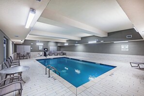 A swimming pool with a tiled deck, lounge chairs, and a lifeguard chair.