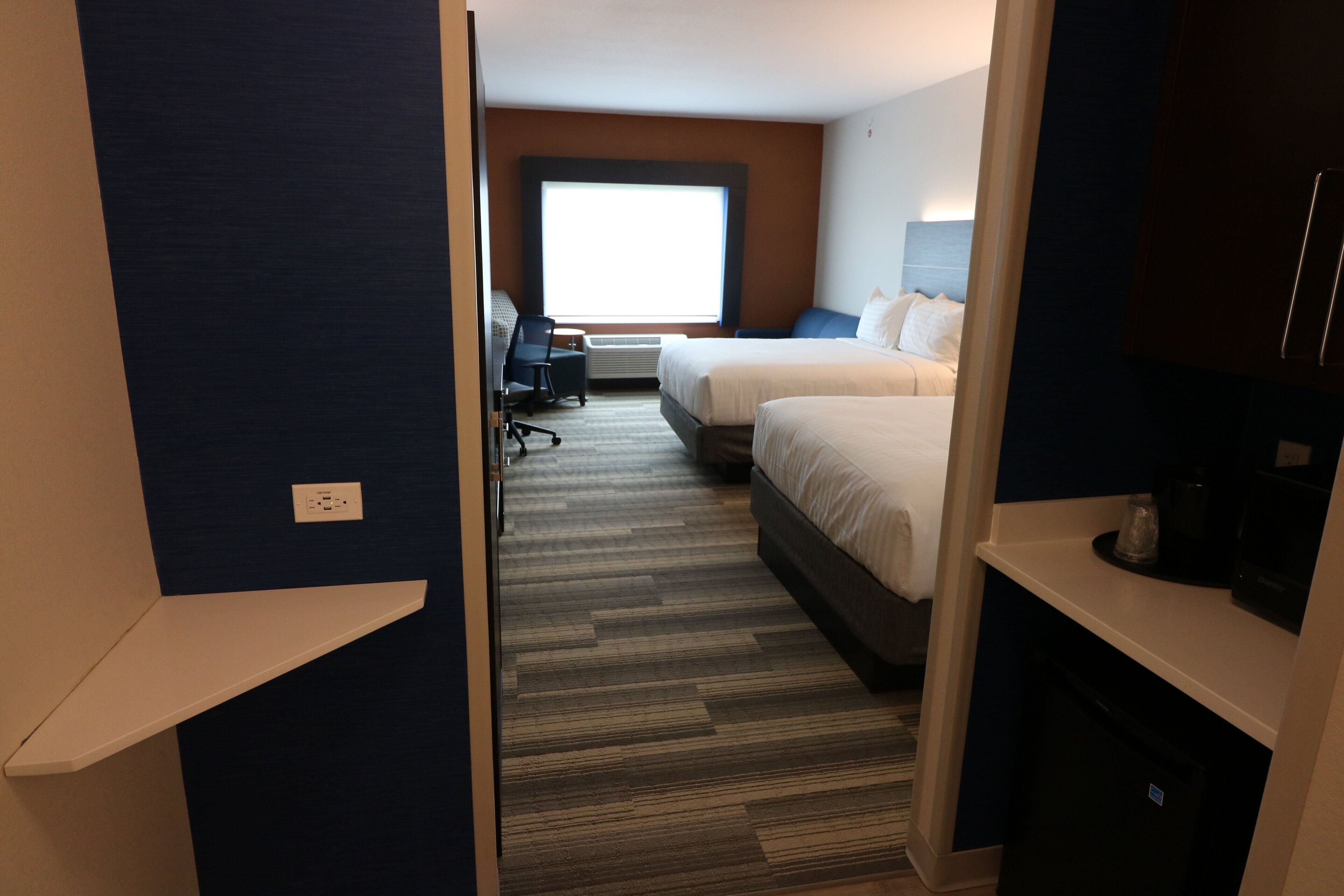 Een hotelkamer met twee bedden, een bureau en een groot raam.