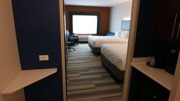 Een hotelkamer met twee bedden, een bureau en een groot raam.