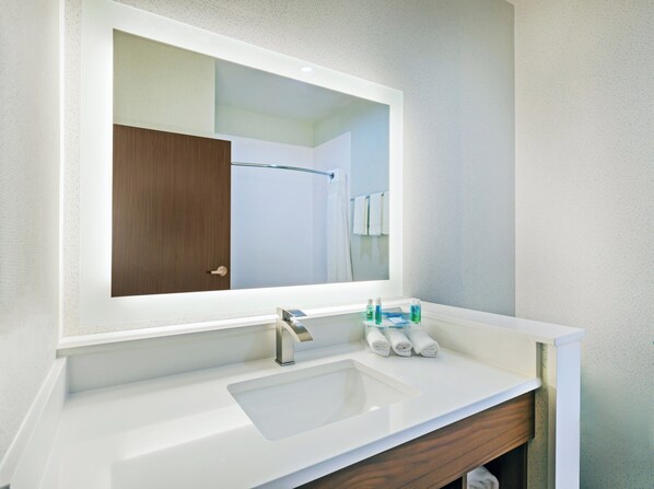 Une salle de bain avec un lavabo blanc, un miroir et un meuble en bois.