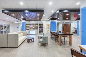 A hotel lobby with seating areas, a reception desk, and a kitchenette. - Holiday Inn Express & Suites Coffeyville by IHG (Coffeyville)