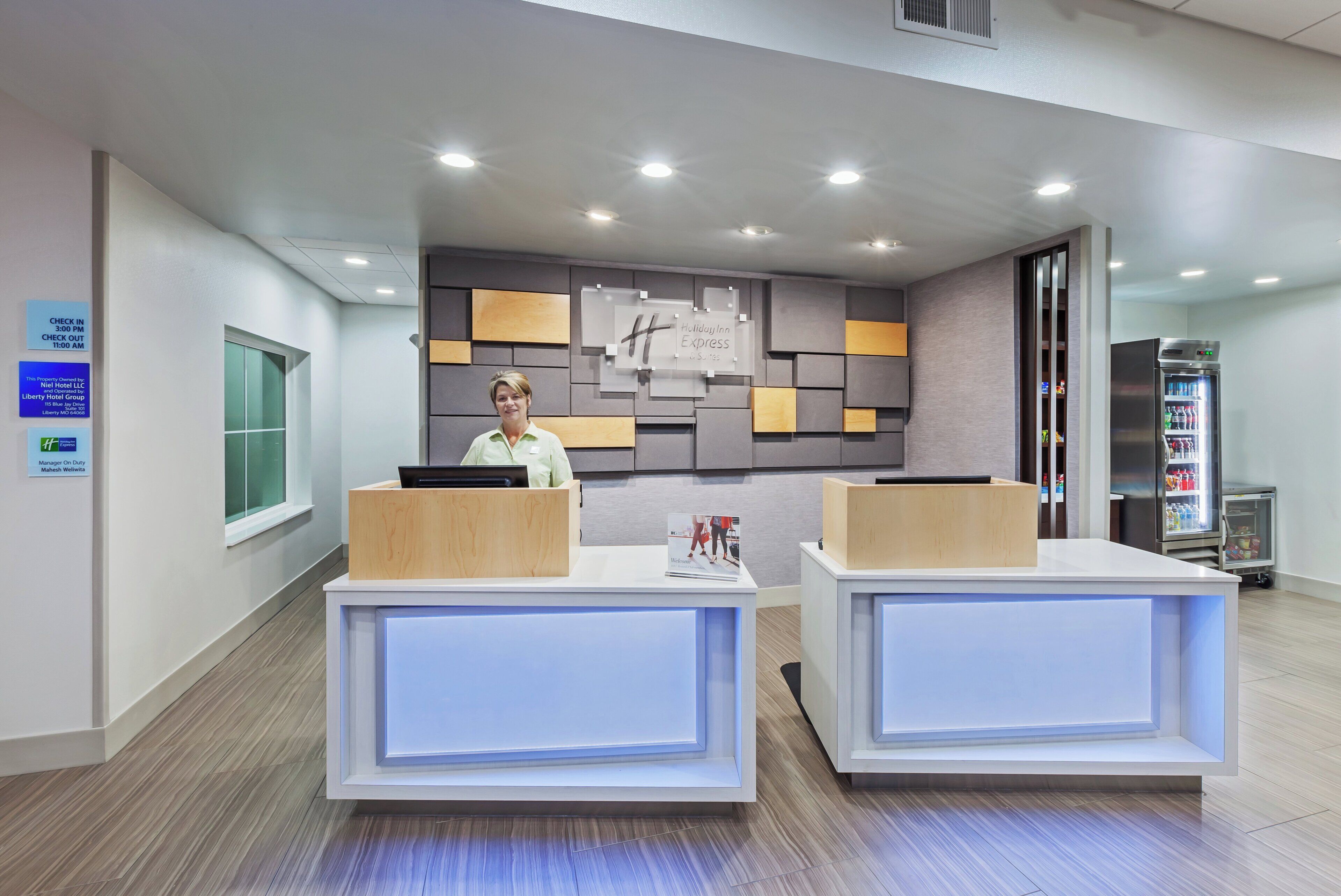A reception desk with a modern design, a digital screen, and a sign indicating check-in times.