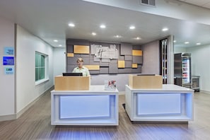 A reception desk with a modern design, a digital screen, and a sign indicating check-in times.